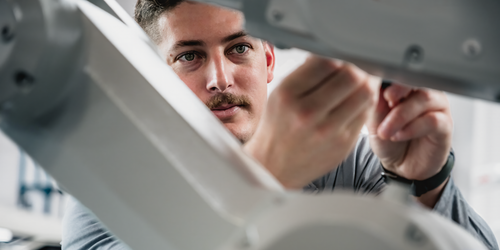 A Kinetic technician focuses on inspecting a piece of maintenance hardware.